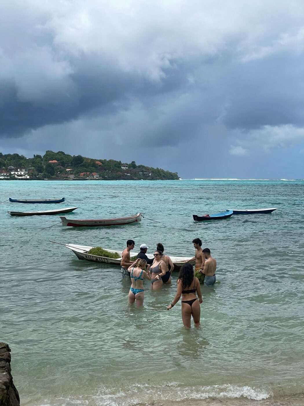 Visitors in the water with seaweed harvest boat in Nusa Lembongan